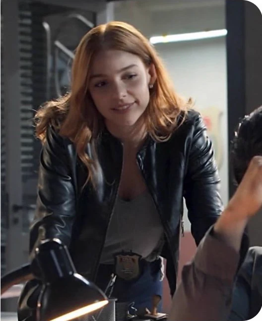 Catarina usando jaqueta escura e distintivo de policial em uma cena da série.