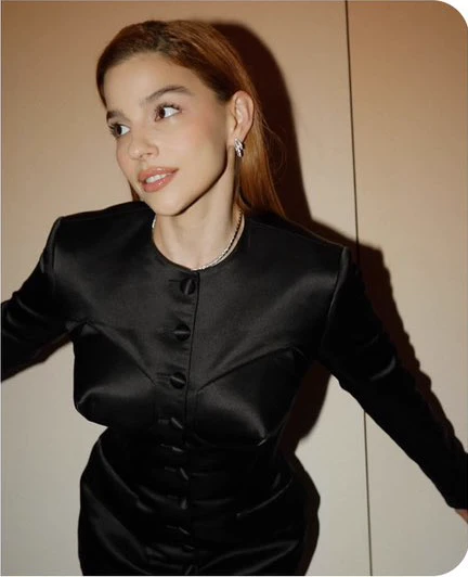 Eduarda Fragoso usando roupa preta, com os braços abertos e apoiados.