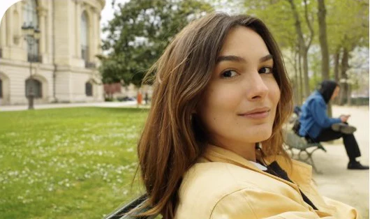 Isabela Alencar sentada em um banco de parque, olhando por cima do ombro.